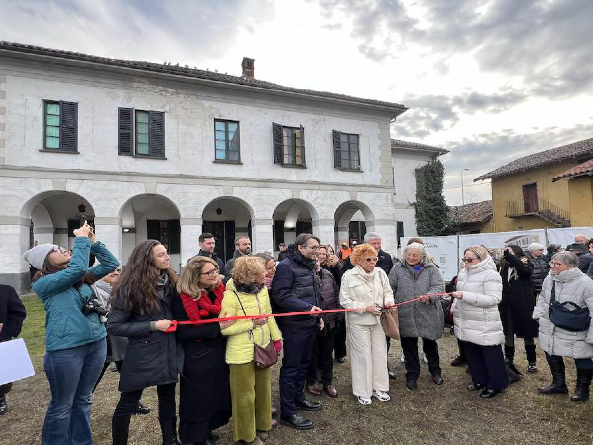 Cascina Ri- Nascita, Milan. Inauguration ceremony of Cascina Ri-Nascita in Milan, featuring a ribbon-cutting by local authorities and community members, set against the backdrop of the restored historic building under a cloudy sky.