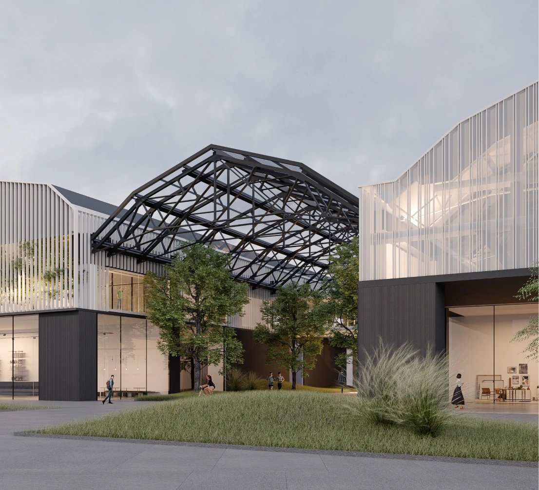 Exterior view of a contemporary architectural complex featuring glass façades and vertical louvers, distinguished by an exposed metal roof structure connecting two main volumes. The green space in the foreground, with trees and people in motion, highlights the integration between industrial architecture and the urban landscape.