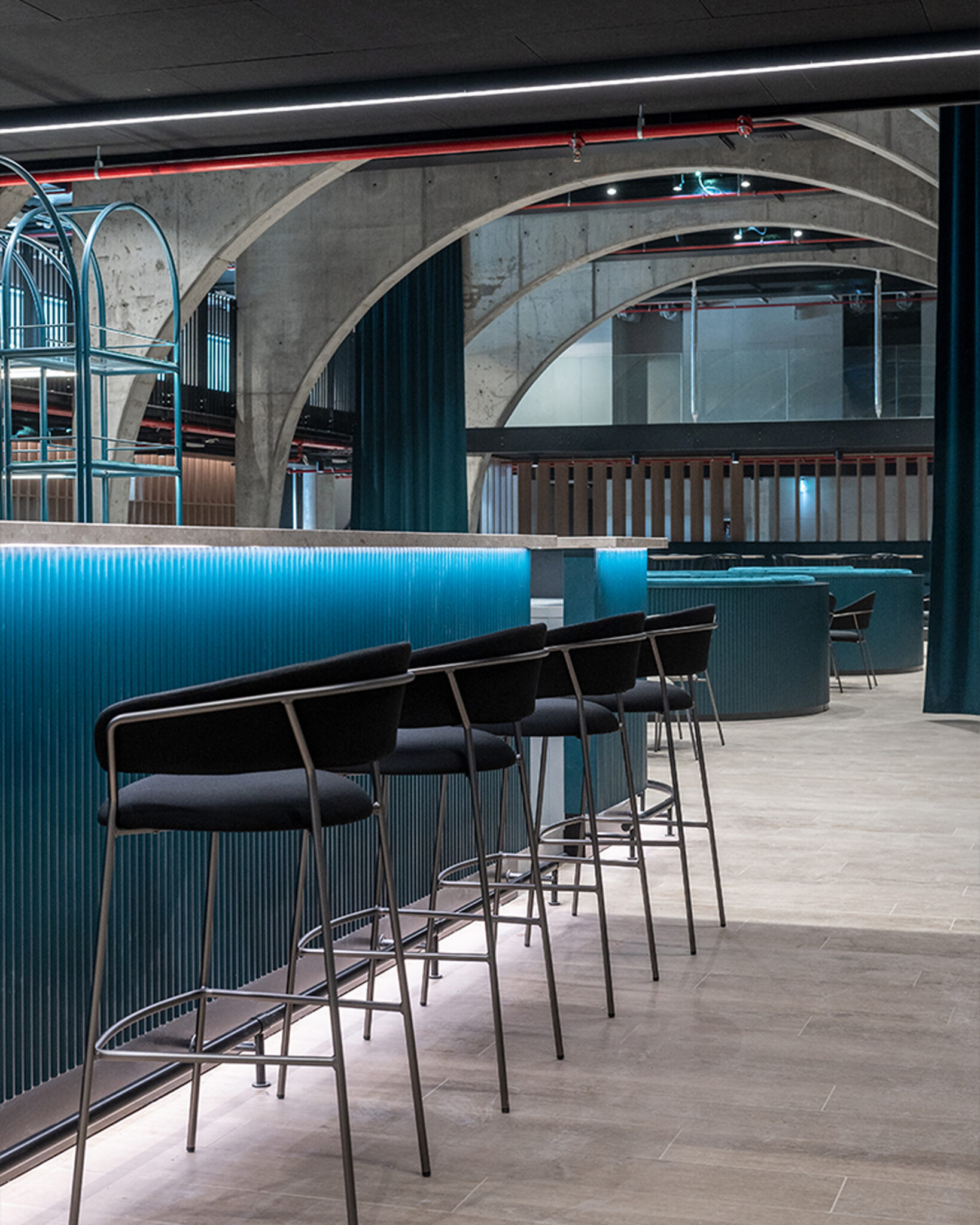 Ristopub ChorusLife, Bergamo. Blue metal counter, designer bar stools, and exposed concrete arches.