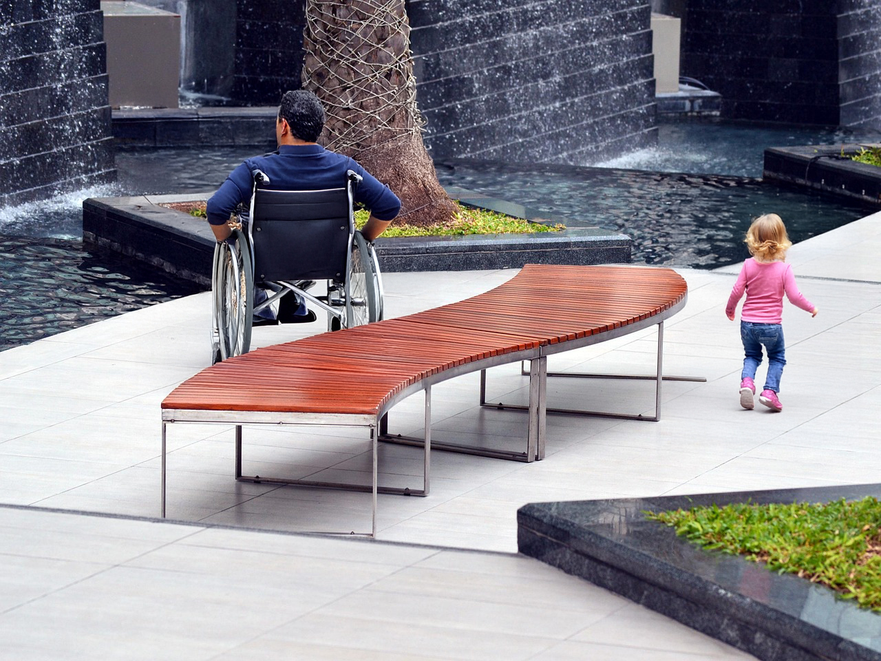 Accessible public space with a man in a wheelchair and a young girl walking, example of inclusive urban design inspired by gender mainstreaming.