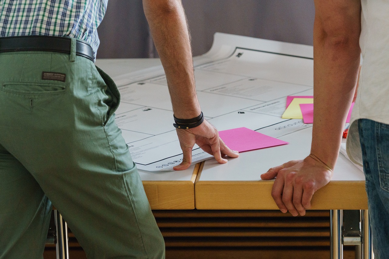 People working on a large sheet with diagrams and colorful sticky notes, during a moment of collaborative and inclusive design.